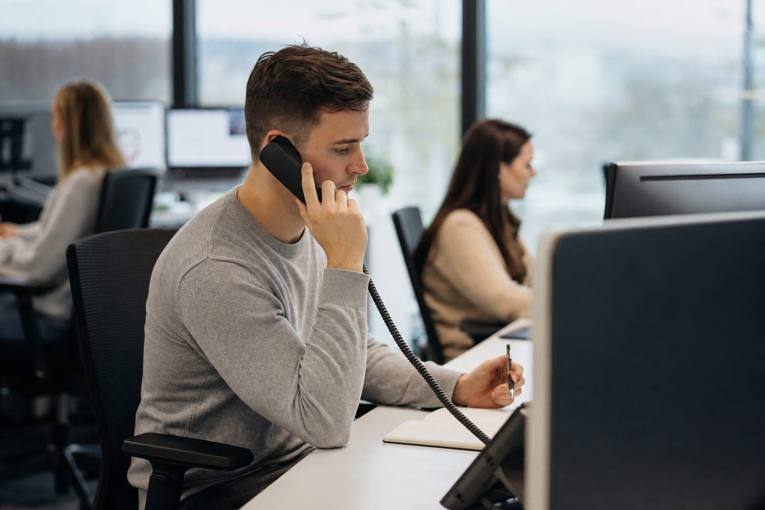 Recruiter im Büro am Telefon, daneben Notizblock und Tischapparat