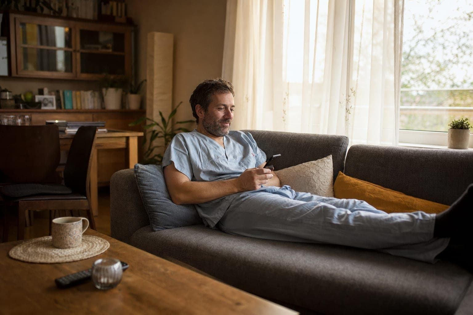 Fachkraft zuhause auf dem Sofa mit dem Telefon in der Hand